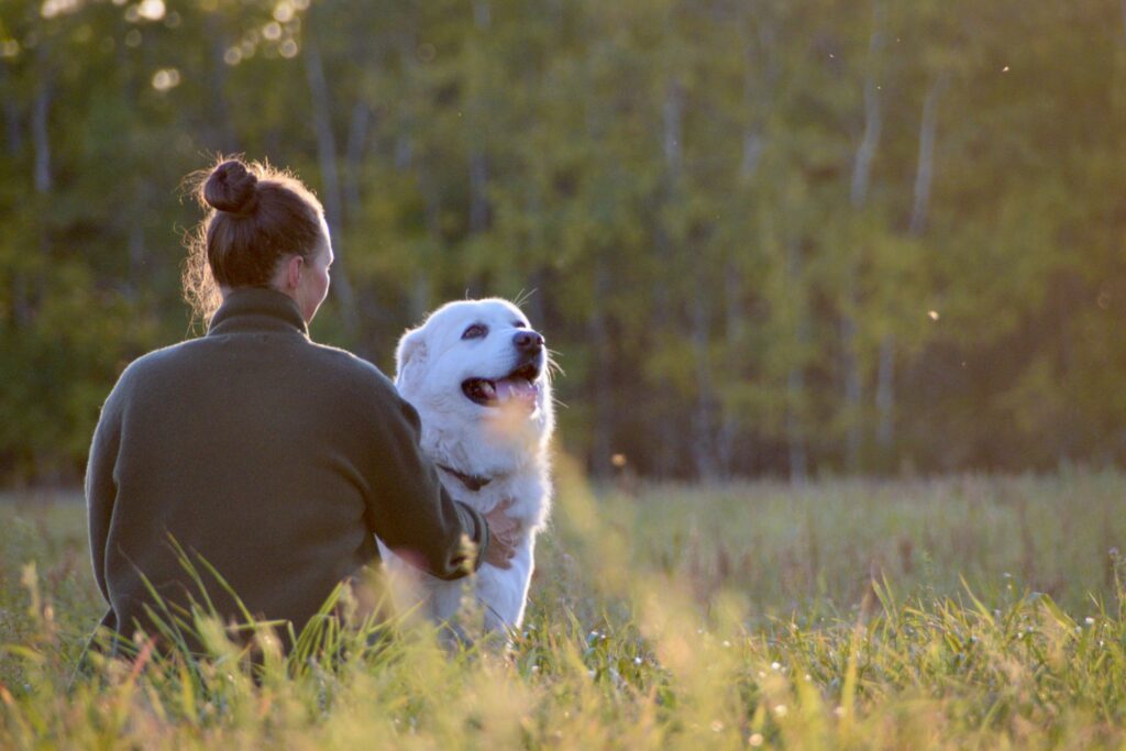 A young woman sitting with her dog, demonstrating a calm nervous system to create emotional safety and co-regulation.